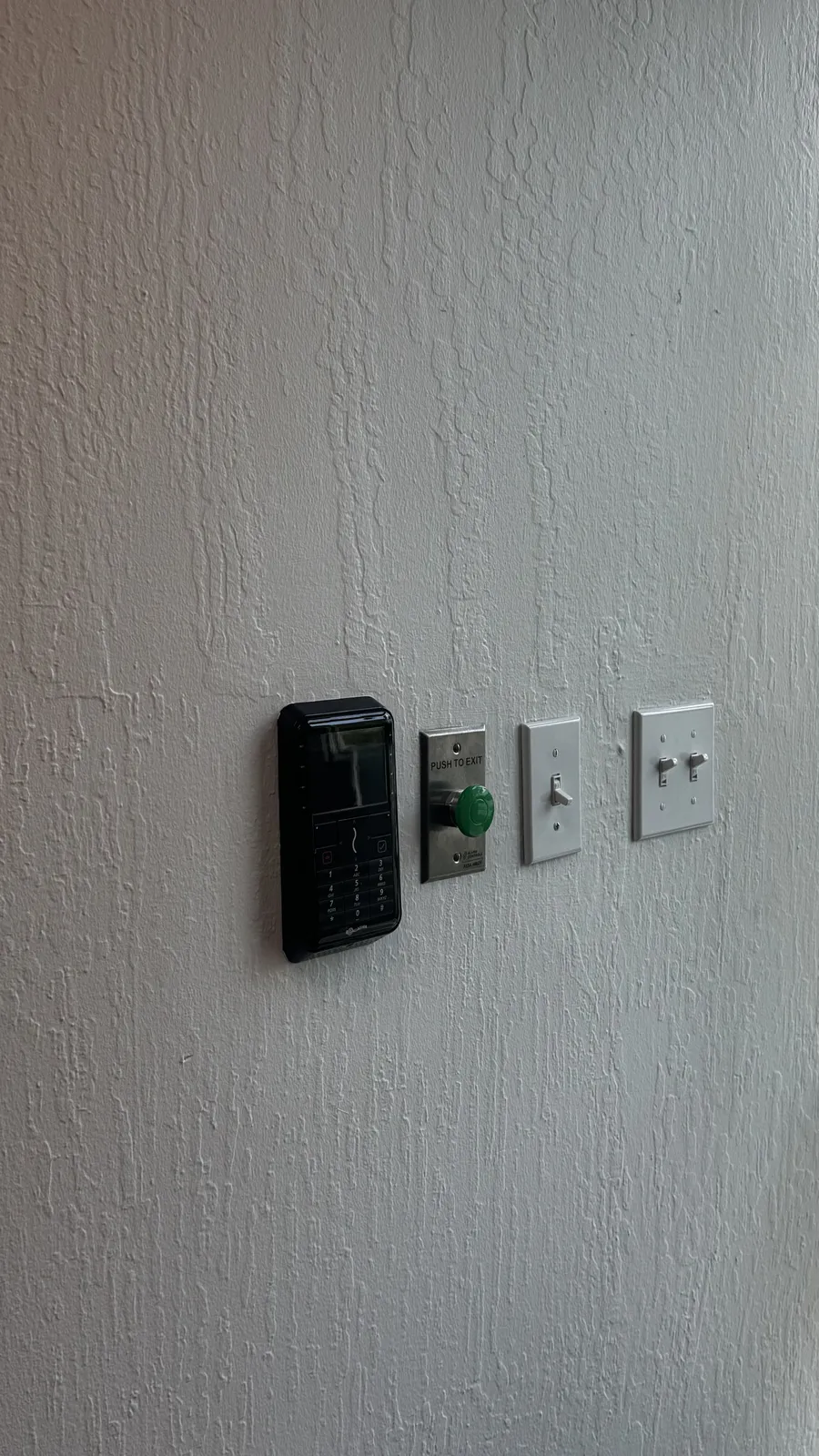 Dual authentication keypad and card reader with a push to exit button beside an interior door