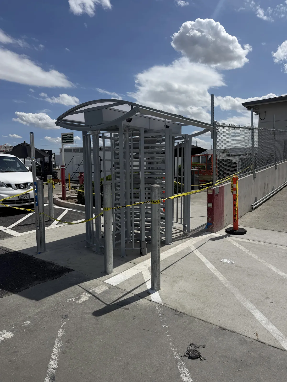 Full-height turnstile with a curved canopy at a fenced vehicle gate