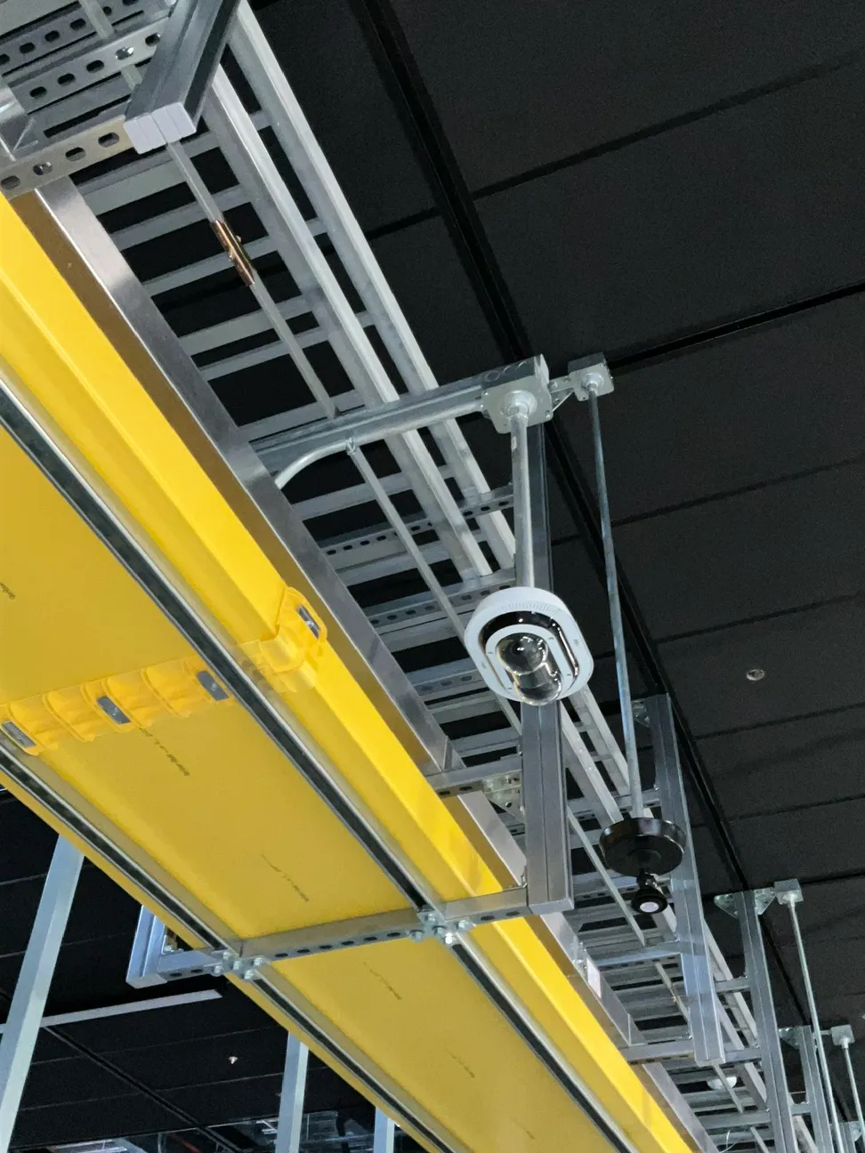 Dual lens camera mounted to overhead strut beside a cable tray and fiber raceway